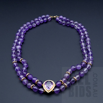 A Double Strand of Amethyst Beads with 9ct Yellow Gold Roundels, at Centre is a Bezel Set Tear Drop Shaped Amethyst