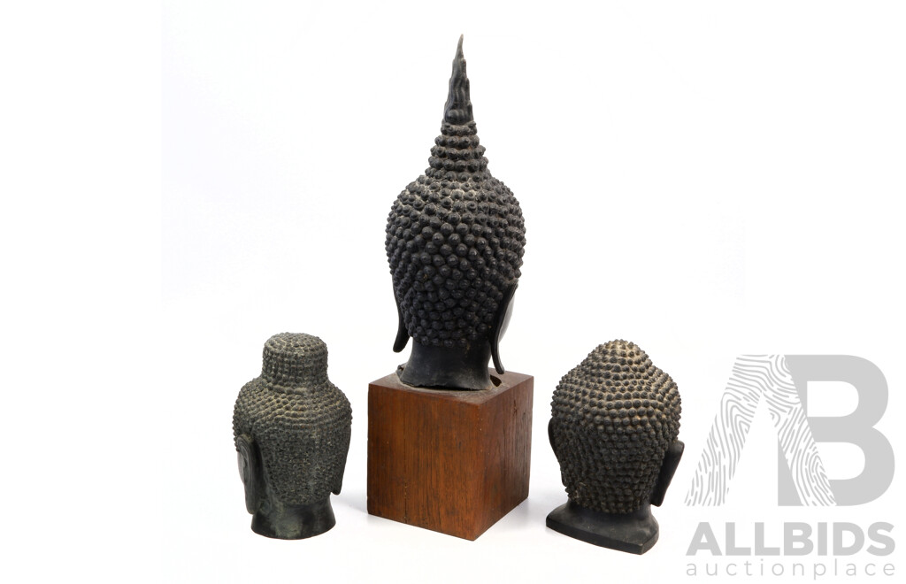 Collection Three Asian Bronze Buddhas Heads, One on Wooden Stand