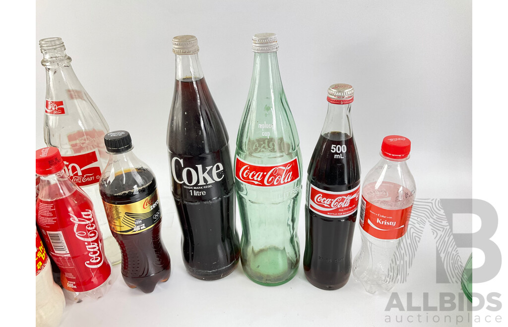 Collection of New and Old Coca Cola Bottles Including Tall Glass One Liter and Plastic T Shirt in a Bottle