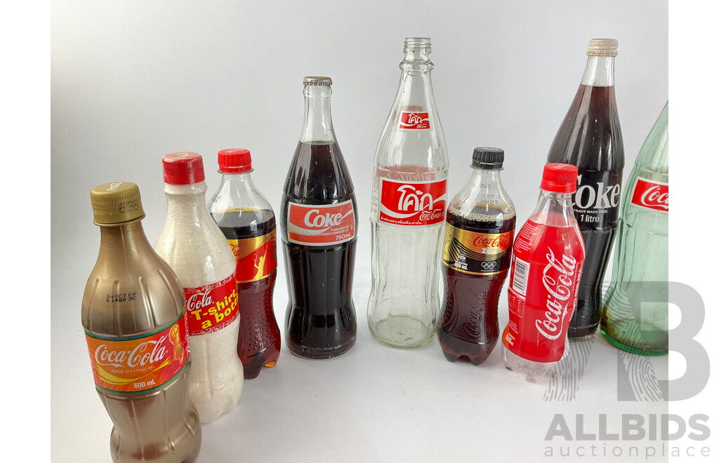 Collection of New and Old Coca Cola Bottles Including Tall Glass One Liter and Plastic T Shirt in a Bottle