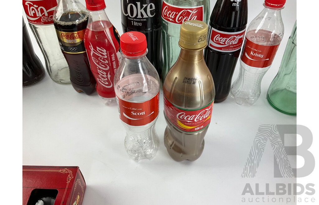 Collection of New and Old Coca Cola Bottles Including Tall Glass One Liter and Plastic T Shirt in a Bottle